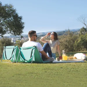 Casal aproveitando um piquenique utilizando espreguiçadeiras portáteis dobráveis em área verde.