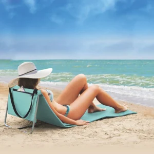Pessoa relaxando na praia utilizando espreguiçadeira portátil dobrável confortável à beira-mar.