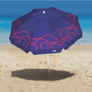 Guarda-sol Campeche Tobee aberto na praia projetando grande área de sombra na areia. Ombrelone azul e rosa com proteção solar ideal para dias ensolarados no mar.