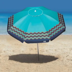 Guarda-sol de praia Tobee na cor azul-turquesa com bordas decoradas em ondas laranjas, aberto na areia fina com o mar ao fundo.