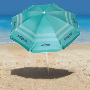 Guarda-sol turquesa com estampa de frase na praia Tobee Ipanema aberto na areia com sombra projetada, servindo como ombrelone moderno e sombreiro articulado para proteção solar.
