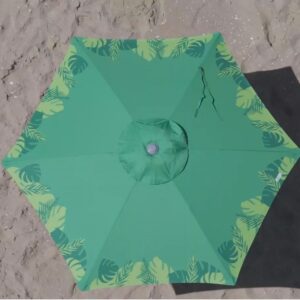 Vista superior de um ombrelone grande verde Tobee, modelo Malibu Beach, aberto na areia da praia, mostrando sua cobertura de proteção solar com estampa de folhas tropicais e sombra projetada.