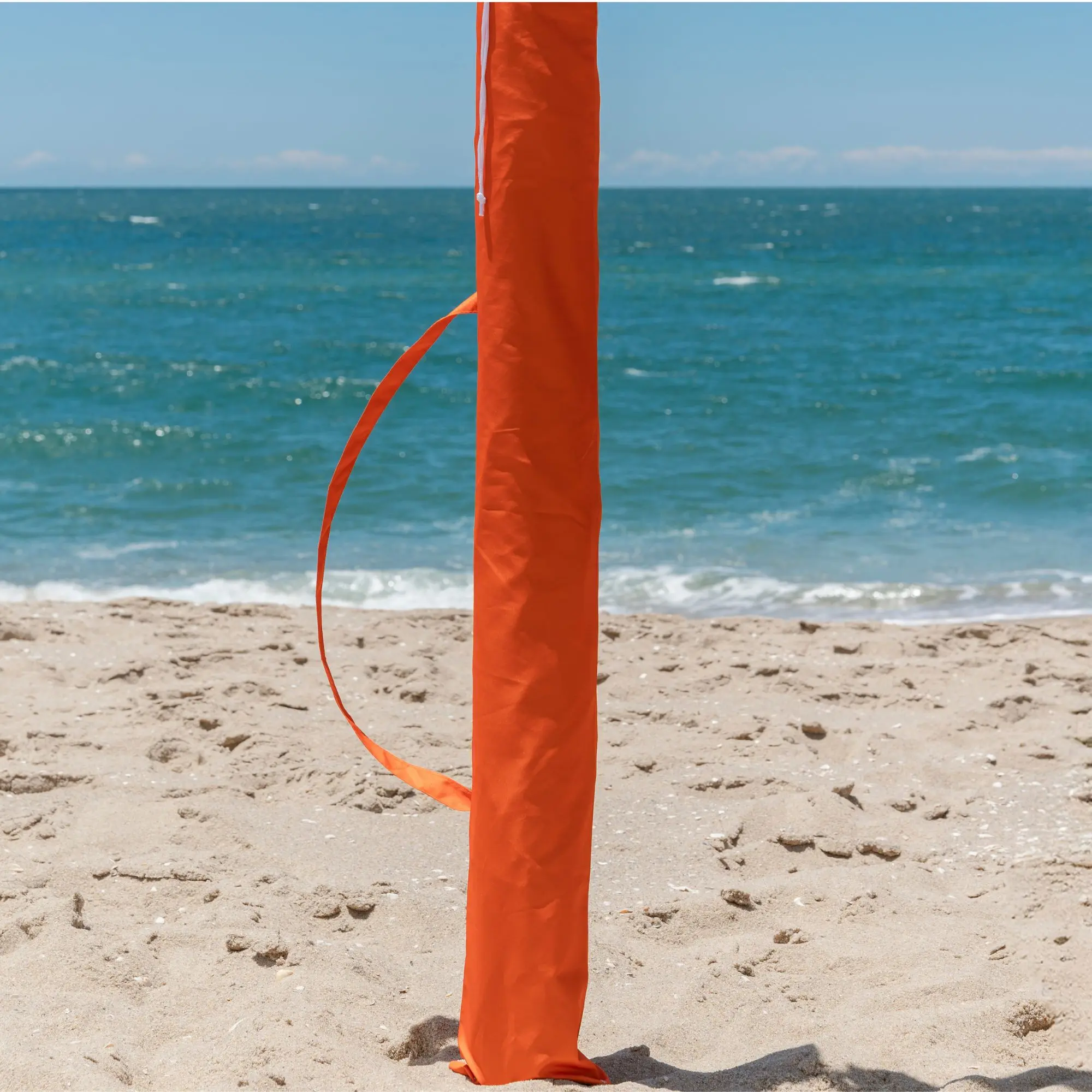 Bolsa e capa de transporte laranja para guarda-sol e ombrelone de praia da marca TOBEE na areia