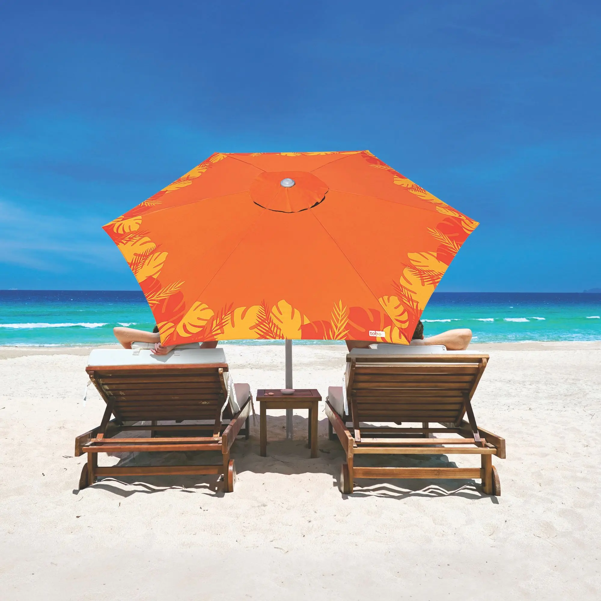 Ombrelone de praia e guarda-sol laranja com estampa de folhas tropicais TOBEE cobrindo espreguiçadeiras na areia