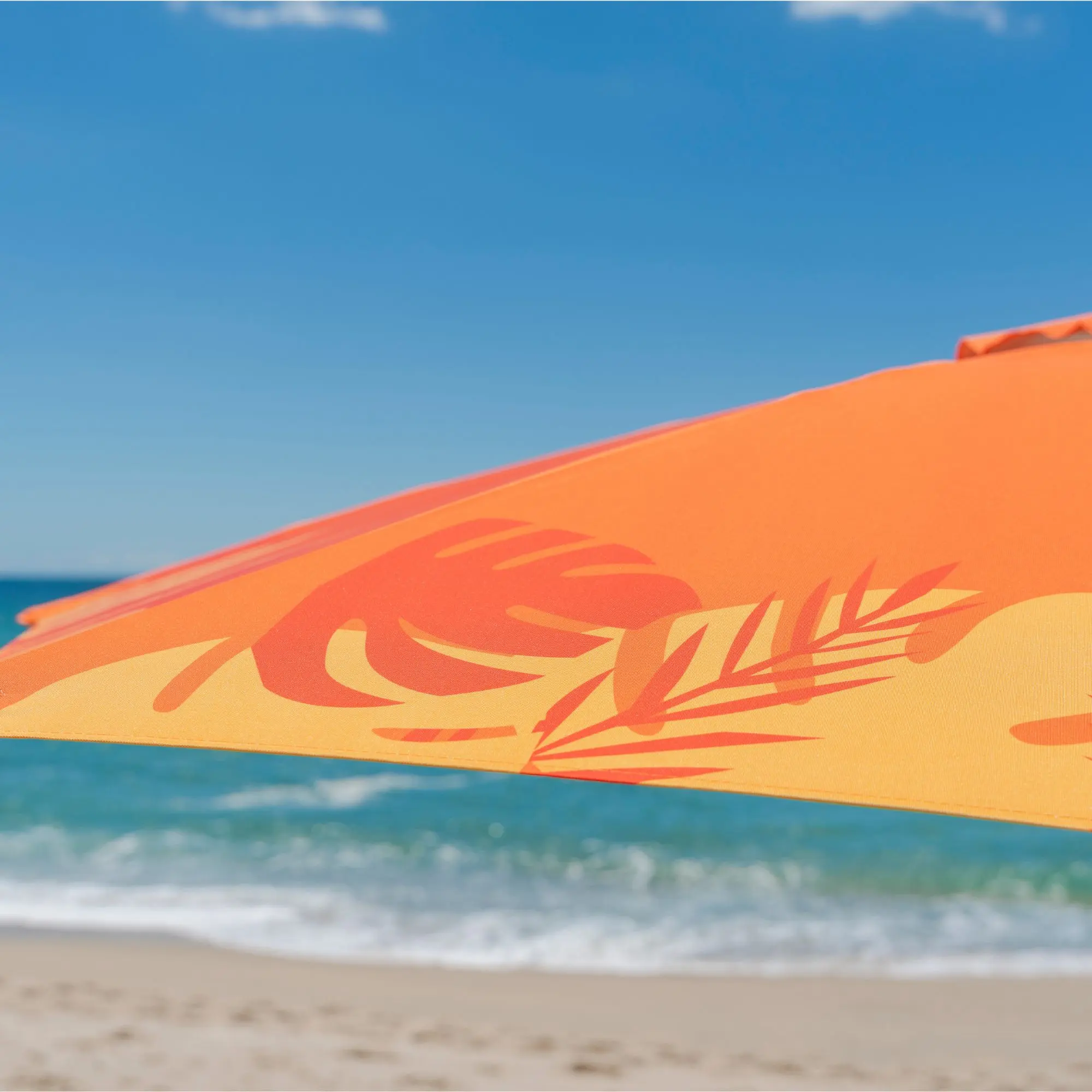 Detalhe em zoom do tecido estampado floral do guarda-sol ombrelone de praia laranja marca TOBEE.