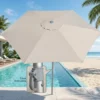 Ombrelone guarda-sol bege aberto na beira da piscina com vista para a praia.