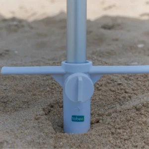 Suporte saca-areia Tobee branco rosqueado na areia da praia fixando um guarda-sol de alumínio.